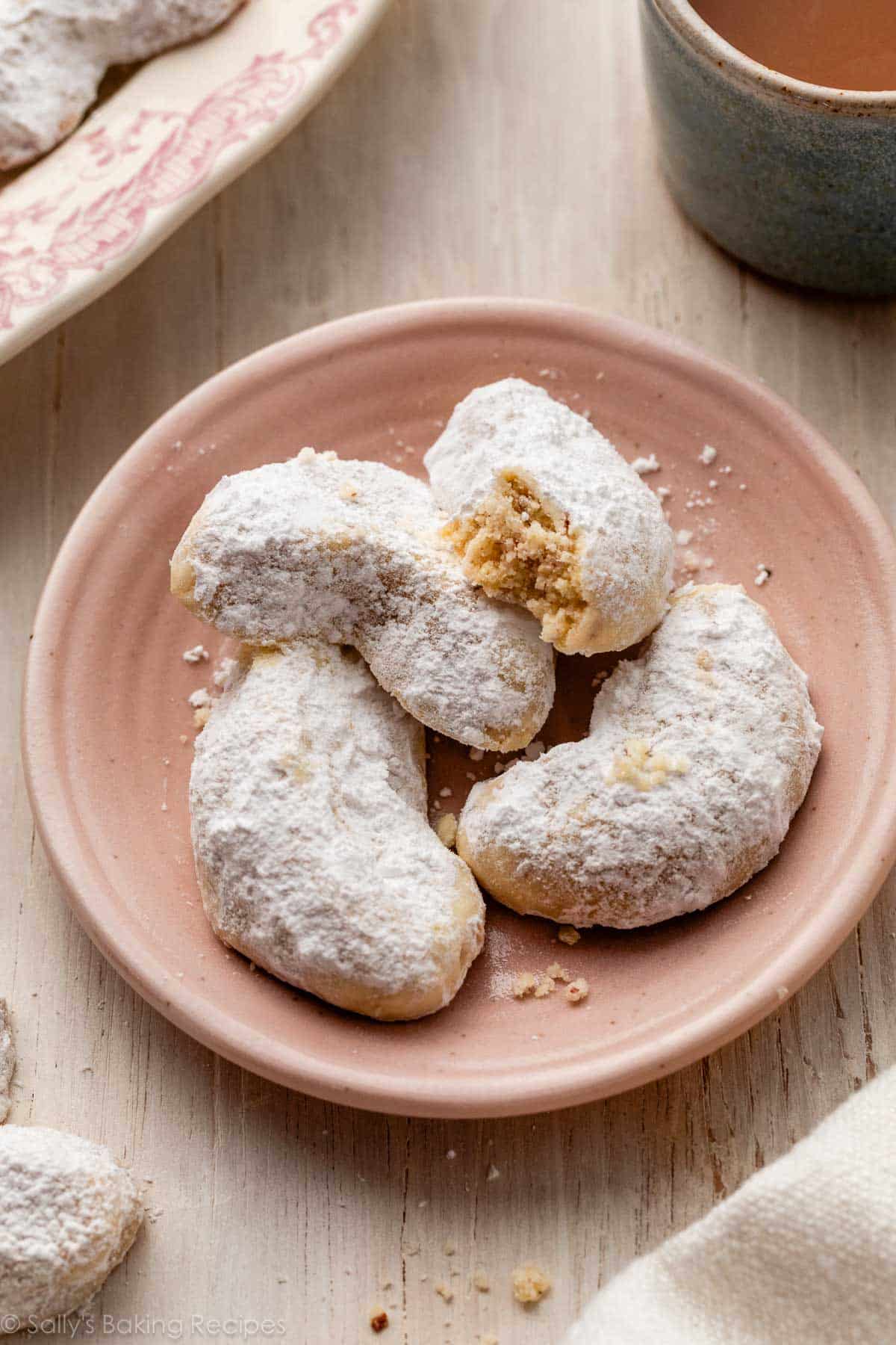 almond crescent cookies on pink plate.