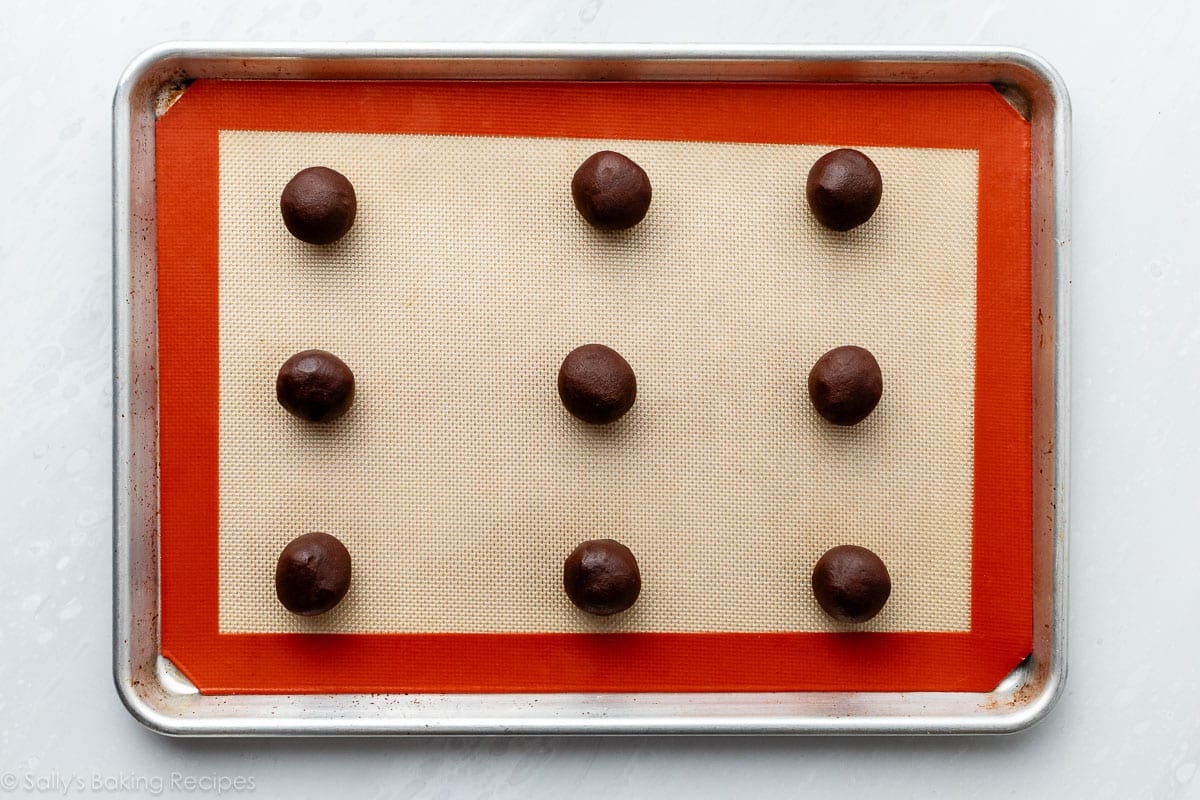 cookie dough rolled into balls on lined baking sheet.