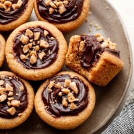 peanut butter fudge puddles with 1 bite taken out on gray plate.