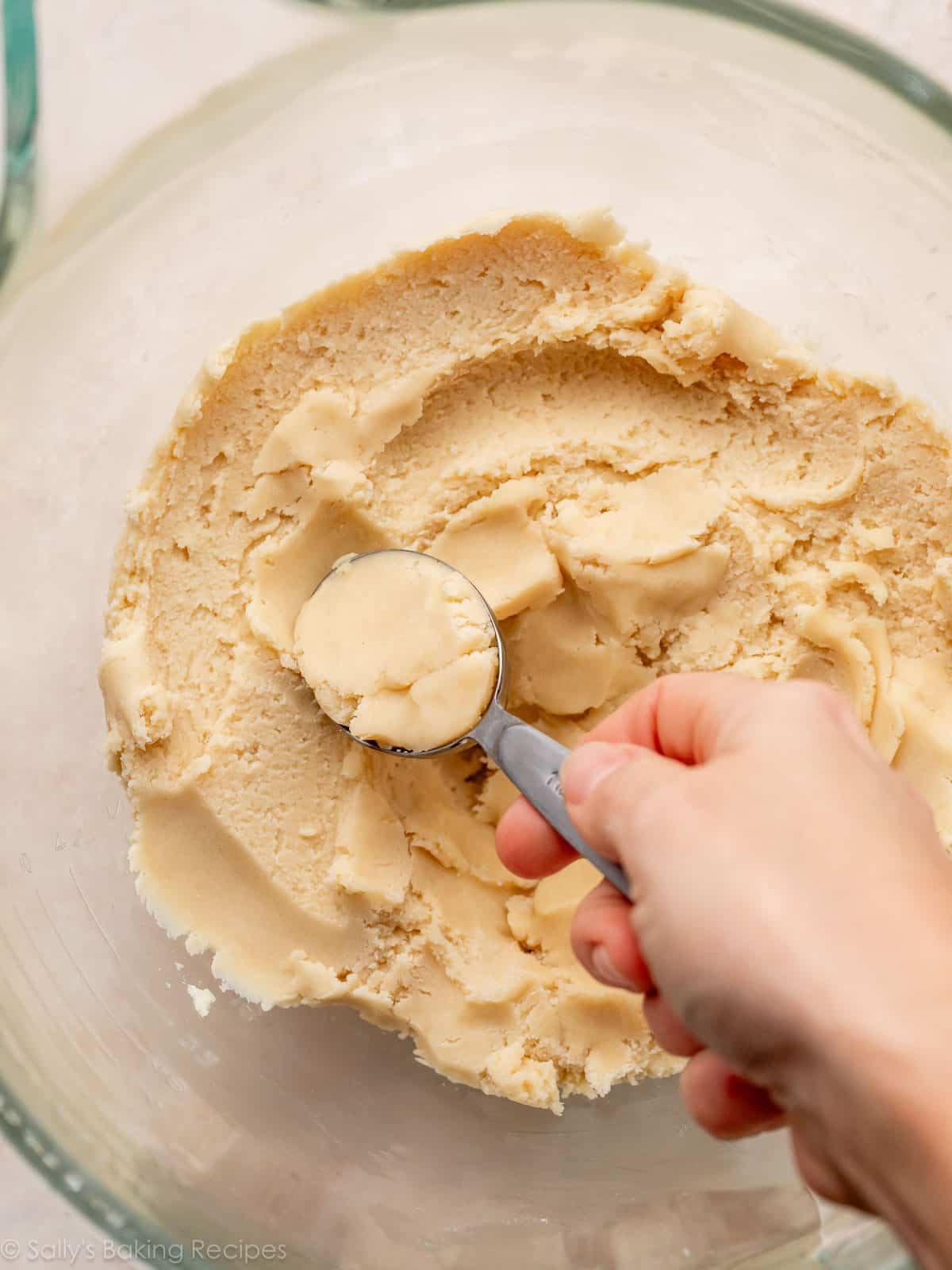 hand scooping up cookie dough with a Tablespoon measuring spoon.
