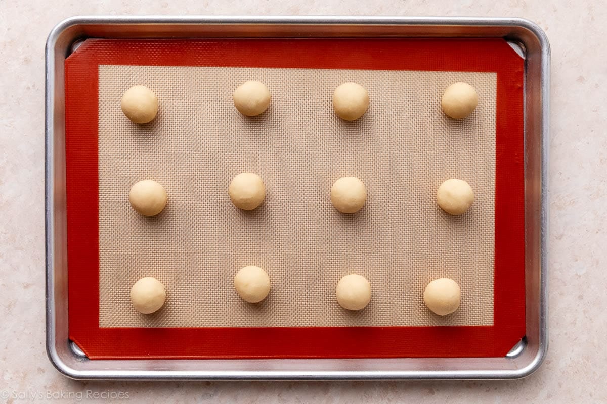 dough balls on silicone baking mat-lined baking sheet.