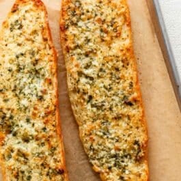 baked homemade garlic bread on parchment paper-lined baking sheet.