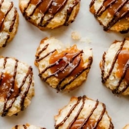 close-up overhead photo of coconut macaroon thumbprints filled with caramel and drizzled with chocolate.