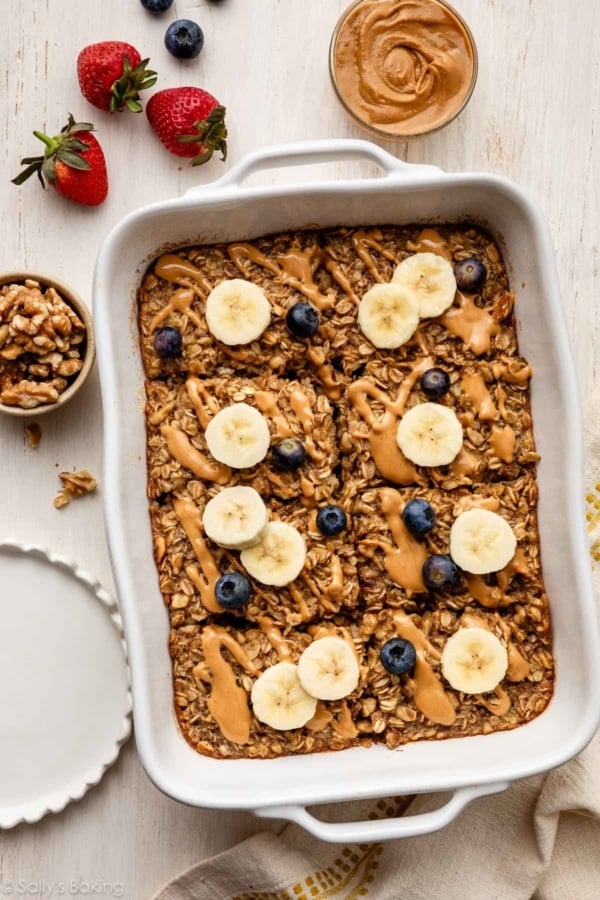 banana baked oatmeal in white casserole dish with blueberries and banana slices.