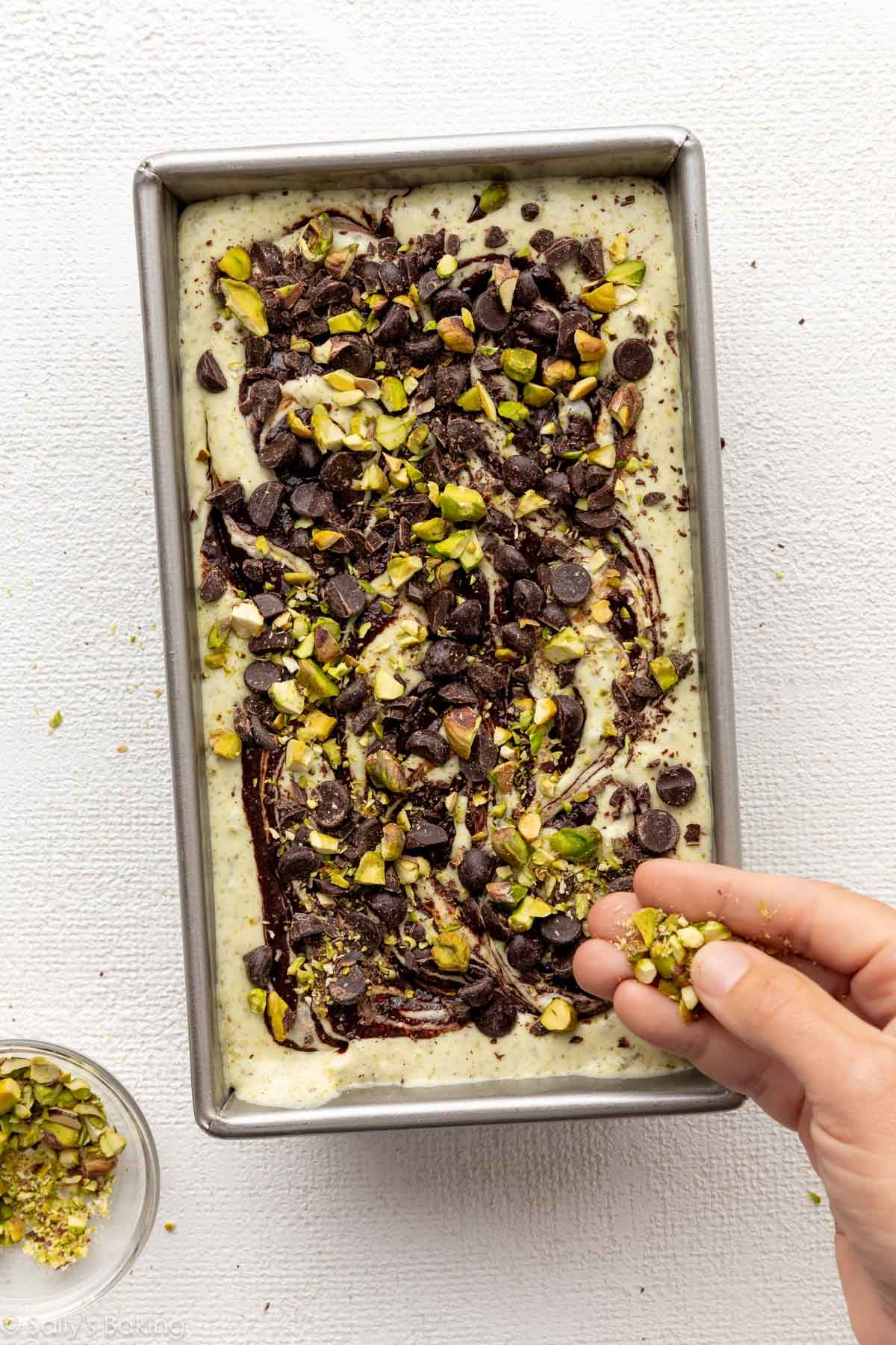 topping pistachio ice cream with chocolate chips and pistachios.