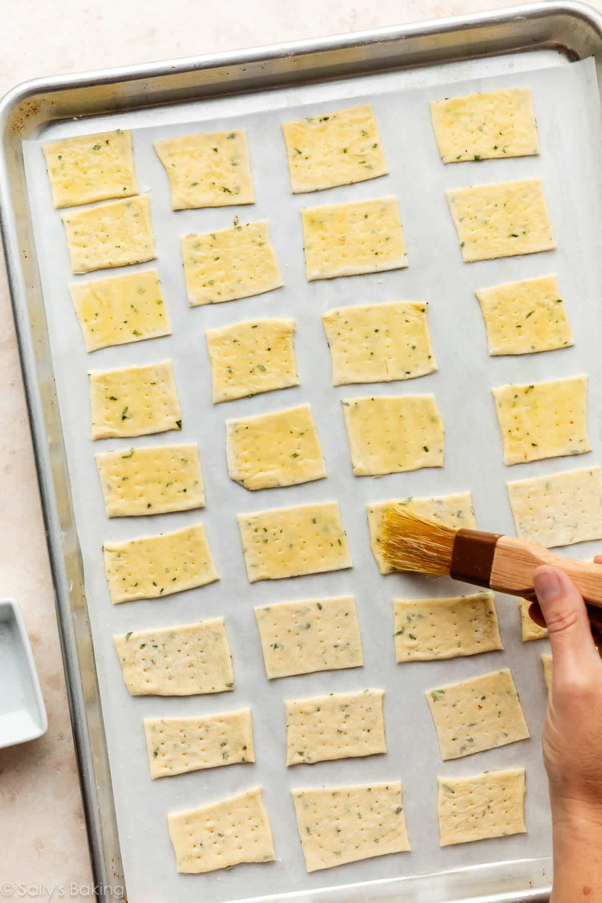 hand brushing olive oil on crackers dough.