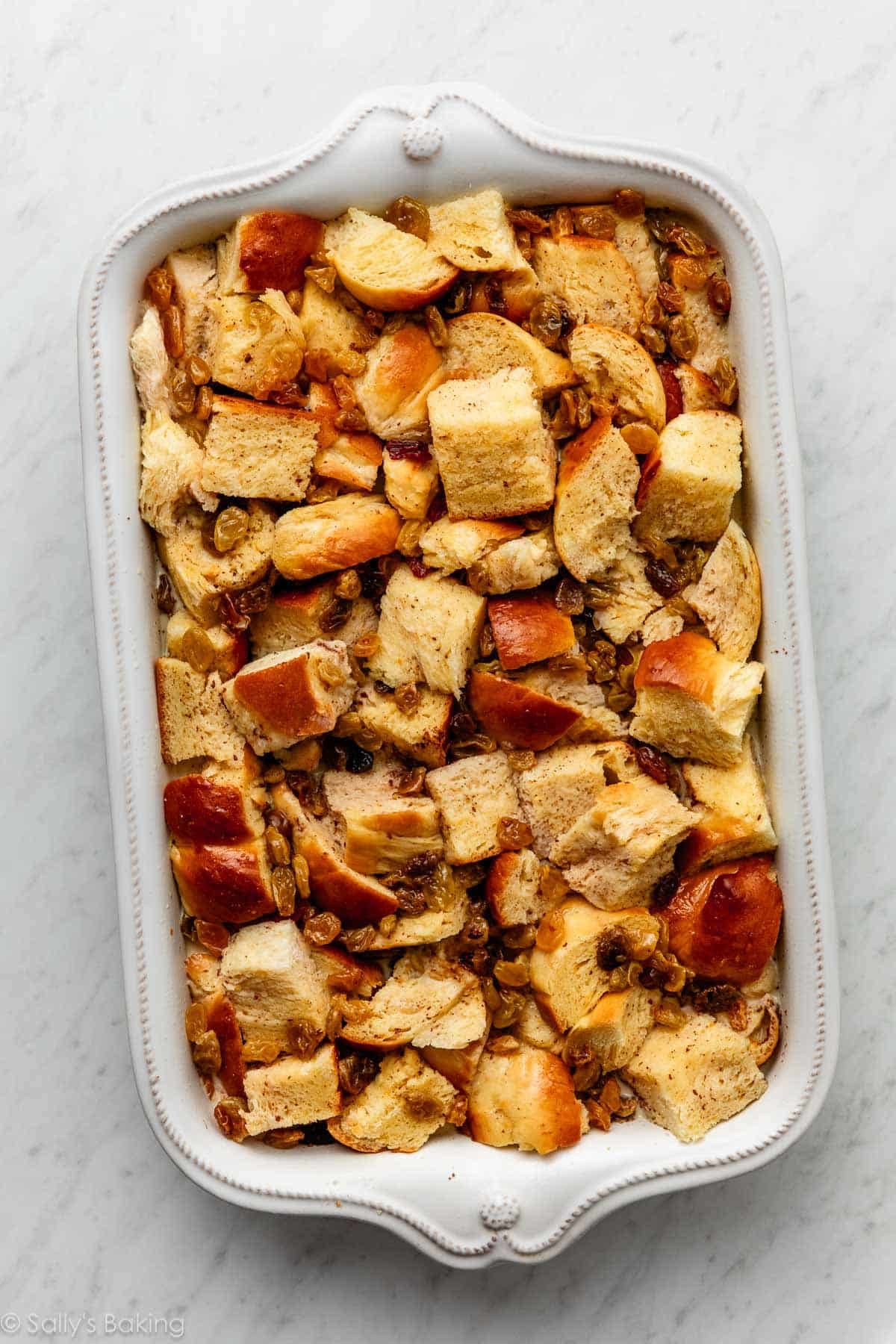 soaked bread and raisins in white casserole dish.