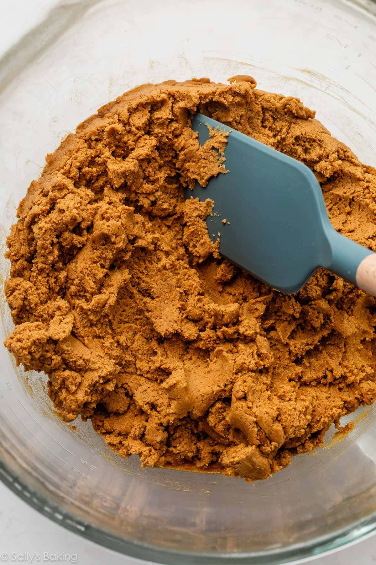 cookie dough in glass bowl with blue spatula.