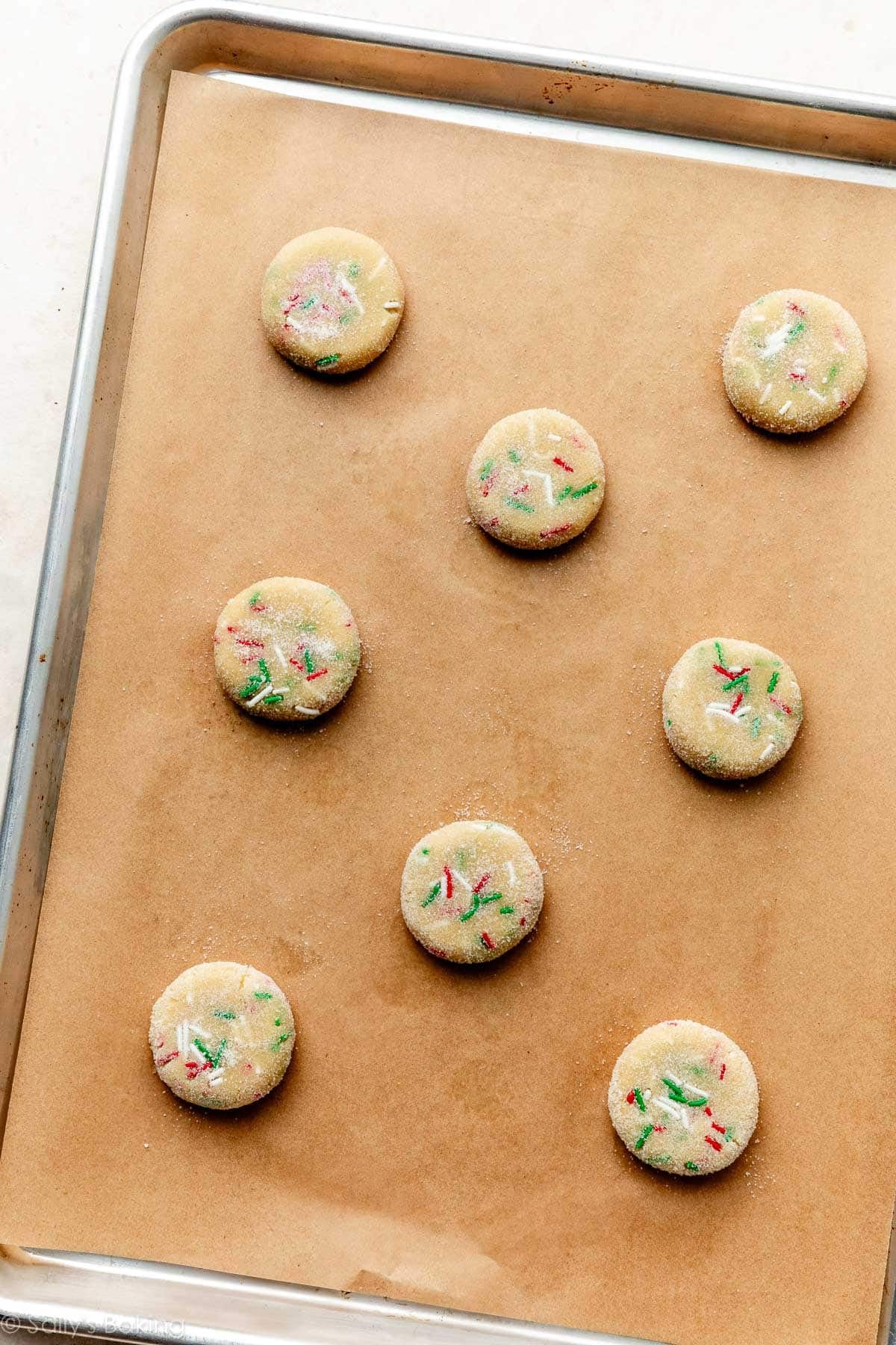 flattened cookie dough balls on lined baking sheet.