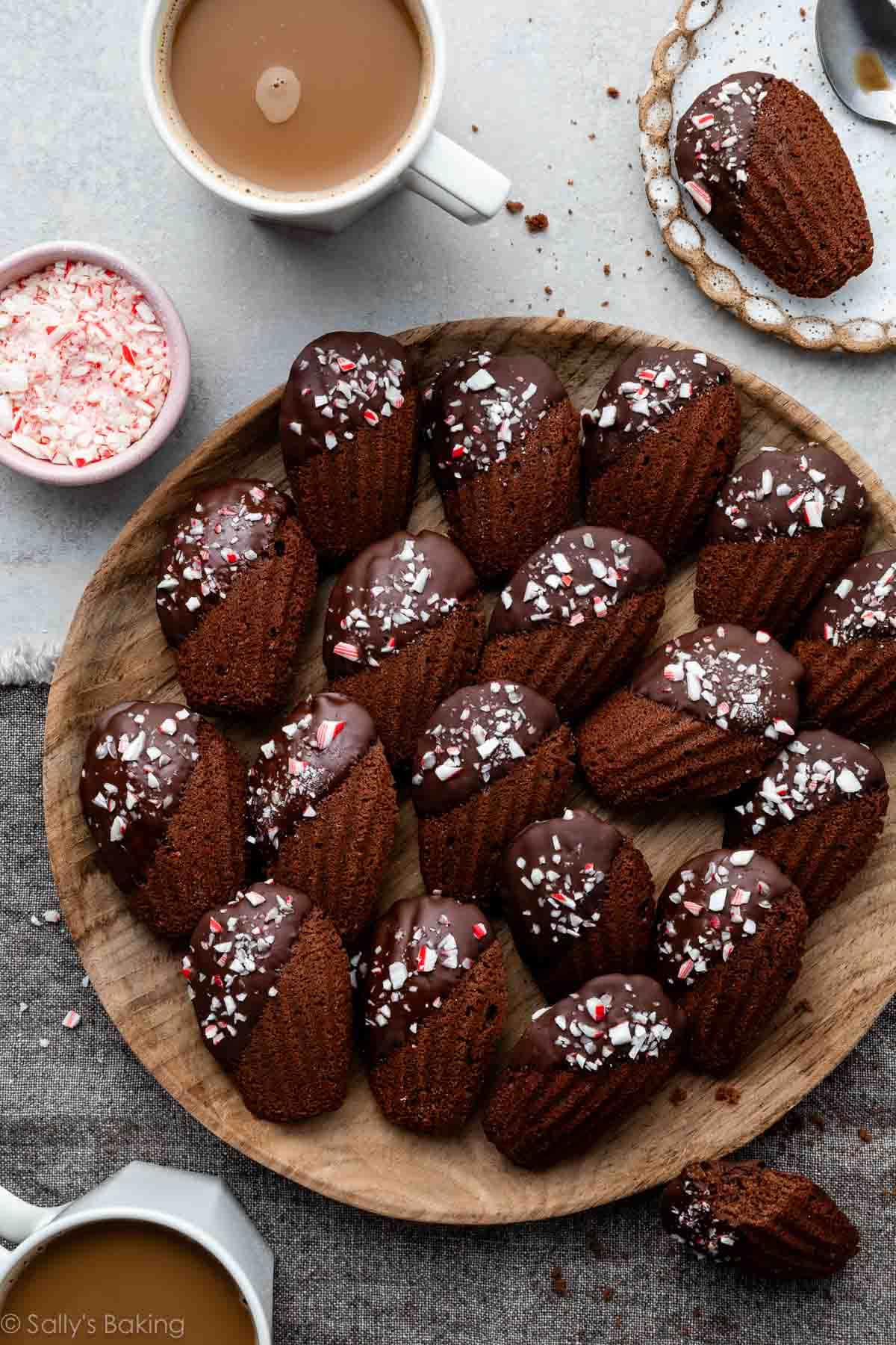 chocolate peppermint madeleines on wooden plate with cups of coffee.